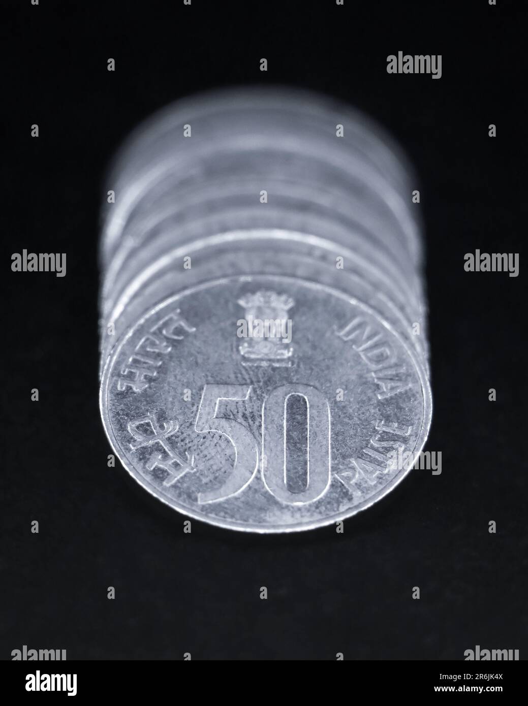 argent vintage brillant cinquante ou 50 pièces paisa de l'inde empilées ensemble dos à dos dans une rangée isolée dans un fond noir en gros plan Banque D'Images