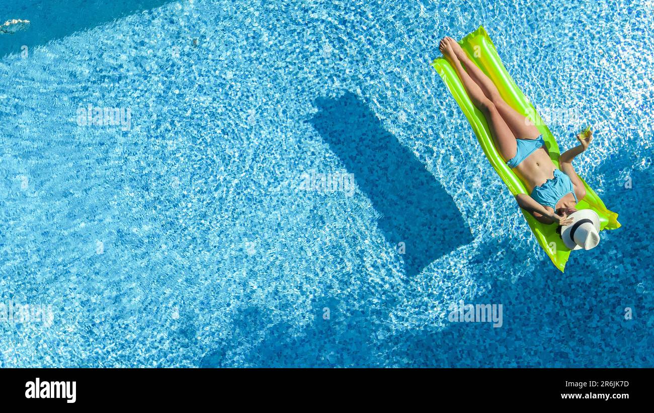 Belle femme en chapeau dans la piscine vue aérienne de dessus d'en haut, jeune fille en bikini se détend et nage sur matelas gonflable et s'amuse dans l'eau Banque D'Images