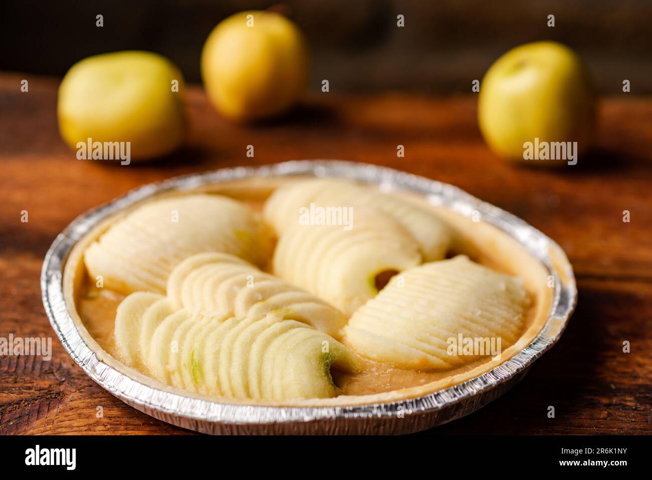 Tarte aux pommes congelée. Pommes en sauce caramel en aluminium sur fond de bois. Banque D'Images