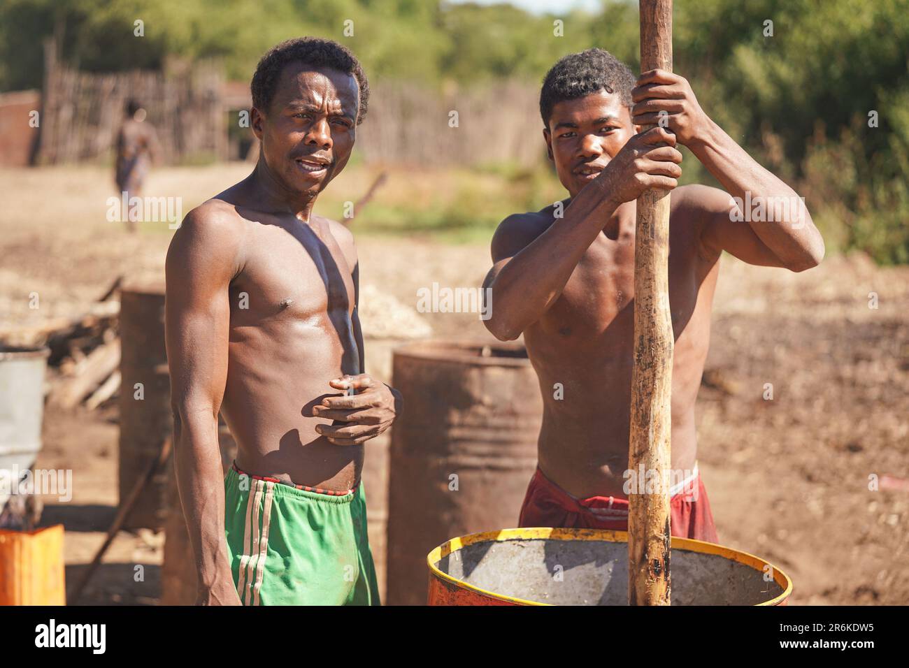 Andanovory, Madagascar - 30 avril 2019: Deux hommes malgaches inconnus qui extraient du jus de fruits dans un grand baril avec un poteau en bois - c'est à utiliser Banque D'Images