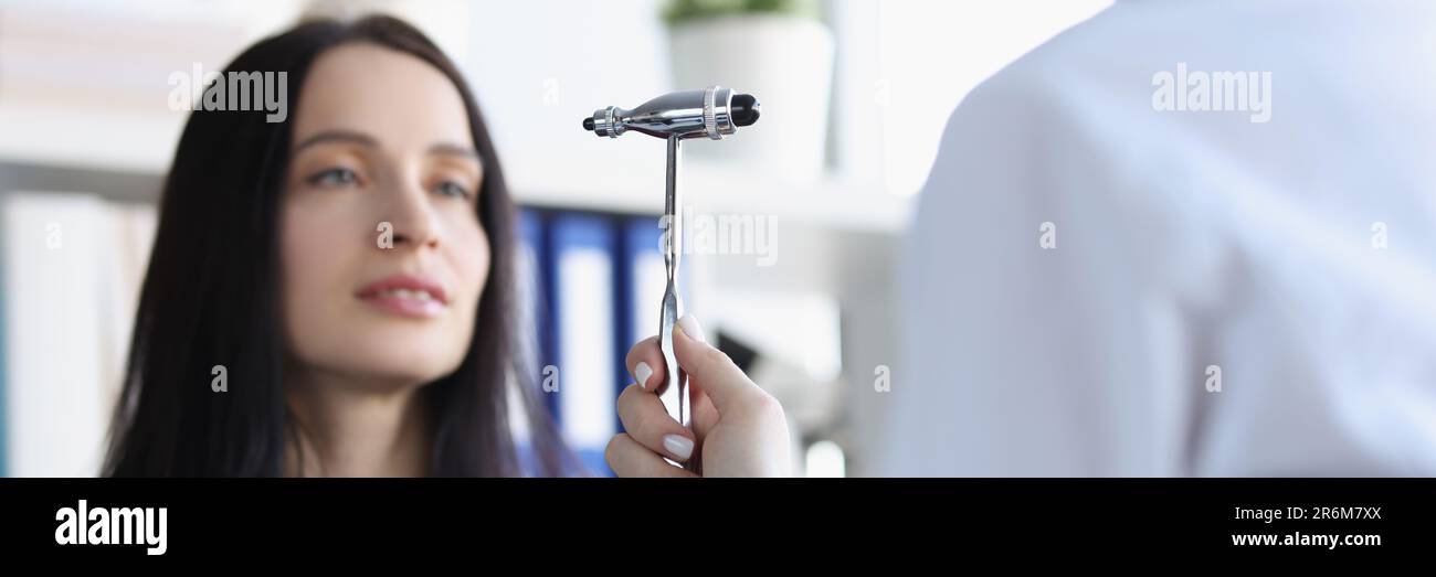 Le neurologue vérifie les réflexes à l'aide d'un marteau spécial tout en examinant une jeune patiente dans un cabinet médical Banque D'Images