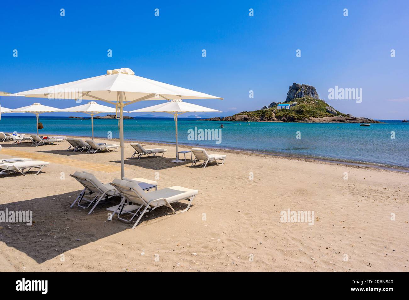 Chaise longue et parasol sur la belle plage d'Agios Stefanos en face de l' île Paradise Kastri - ruines historiques et paysage paradisiaque sur la  côte de l'île Photo Stock - Alamy
