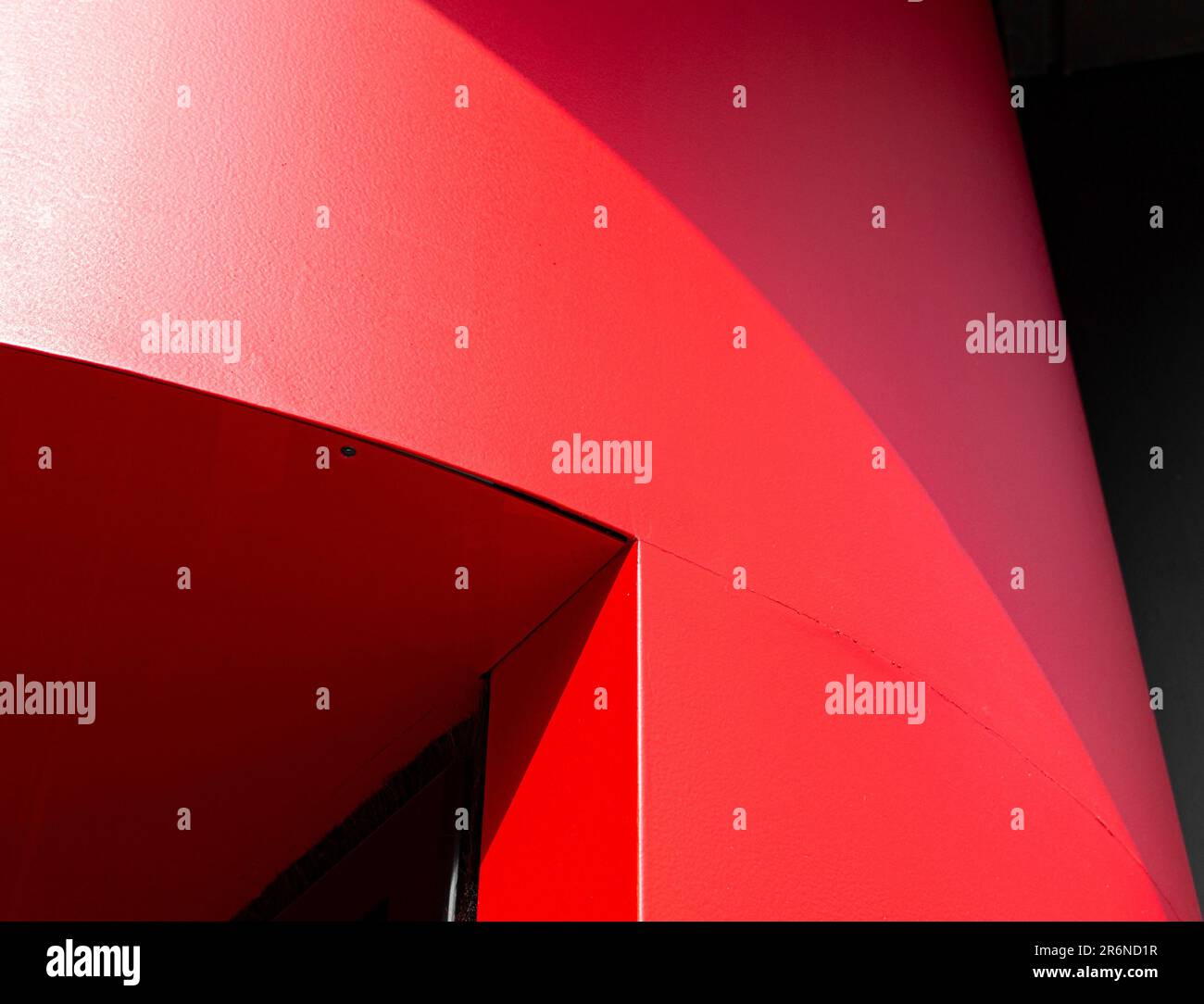 Objet rouge abstrait isolé sur un fond noir, avec des lignes courbes et une base plate Banque D'Images