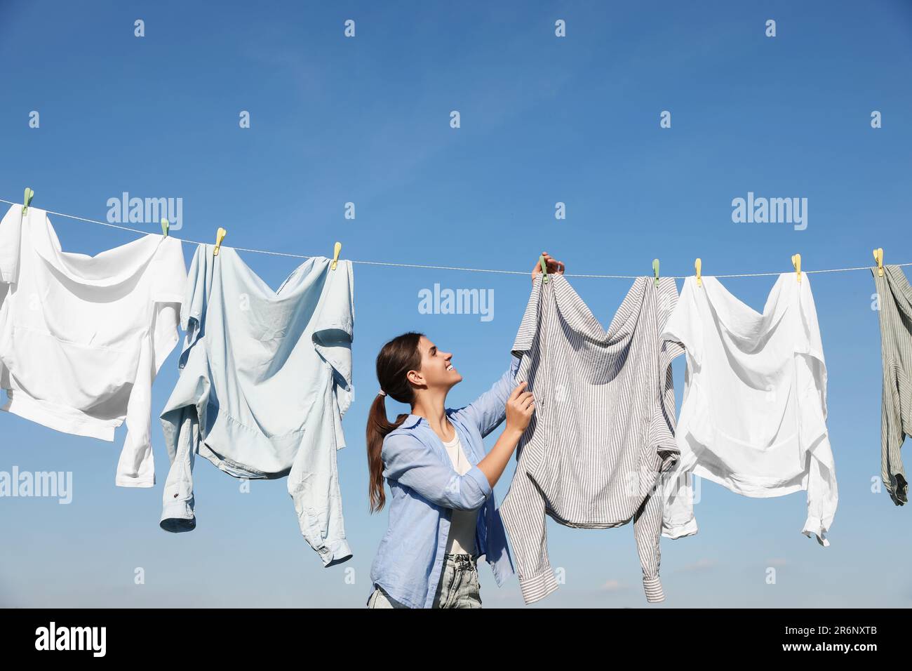 Femme accrochant des v??tements avec des ?�pingles ?� linge sur la ligne de lavage pour s?�cher 