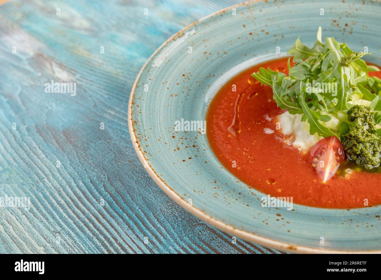 Soupe de tomate chaude au fromage crémeux et au pesto et à l'arugula sur fond de bois bleu. restaurant servant Banque D'Images