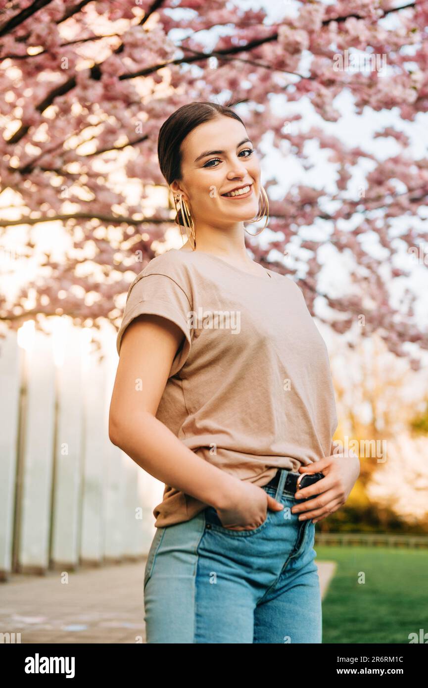 Portrait extérieur de la belle fille de 18-20 ans posant dans le jardin fleuri Banque D'Images