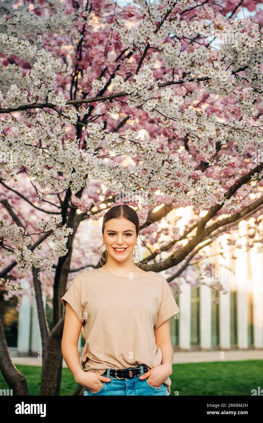 Portrait extérieur de la belle fille de 18-20 ans posant dans le jardin fleuri Banque D'Images