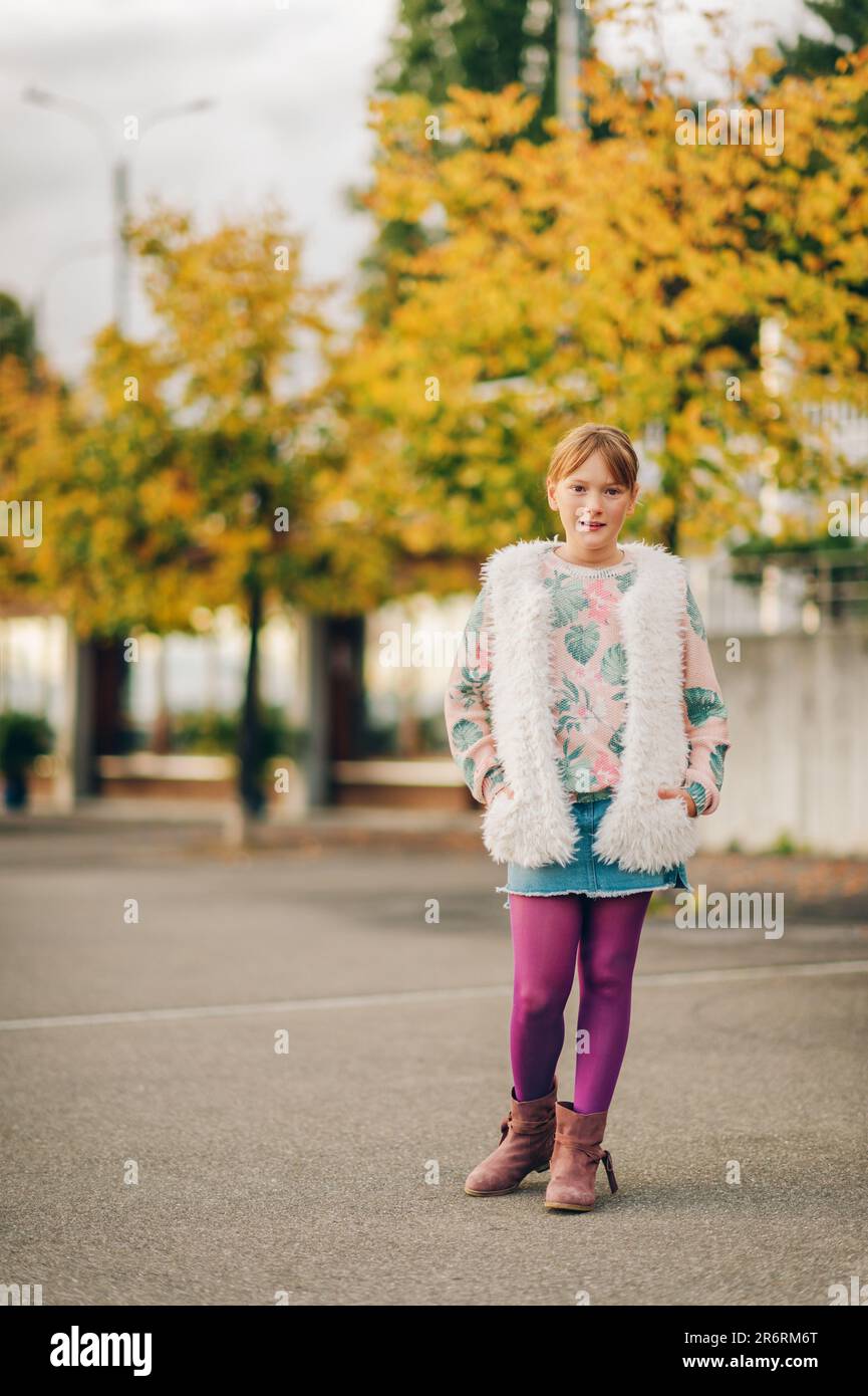 Portrait de mode en plein air d'une jolie petite fille portant un pull-over  élégant, une veste sans manches en fausse fourrure blanche et des collants  violets Photo Stock - Alamy