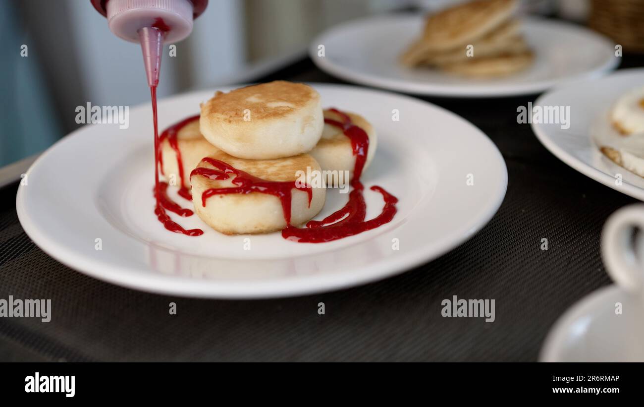 Sirop verse sur une macro photo d'une crêpe. Goutte de sirop gros plan. Le sirop d'érable se verse sur une pile de crêpes au ralenti. Nourriture sucrée pour le petit déjeuner Banque D'Images
