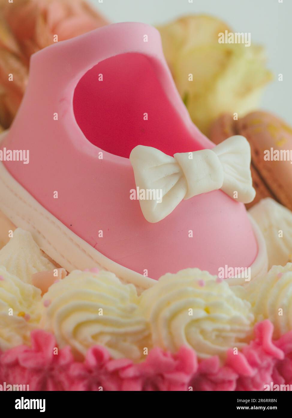 Présentoir à gâteaux rose pour chaussures bébé avec affiche pour garçon ou fille pour douche bébé sexe révélez le gâteau à la crème cilindrical givré au beurre. Banque D'Images