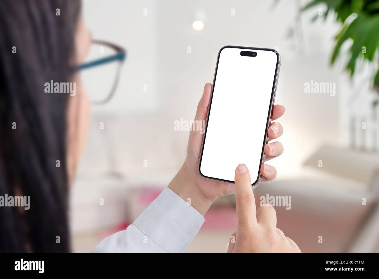 Un jeune adulte, vêtu d'une chemise blanche, utilise un smartphone avec écran vide à l'intérieur. Écran isolé pour maquette, présentation d'application. Banque D'Images