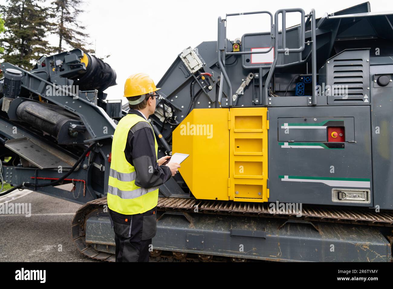 Concevoir avec une tablette numérique à côté de la machine de construction routière. Banque D'Images
