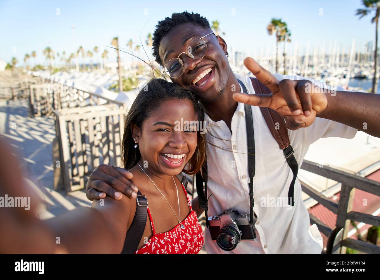 Joyeux jeune couple touristique africain appréciant des vacances d'été dans la station balnéaire de la ville prenant des selfies. Banque D'Images