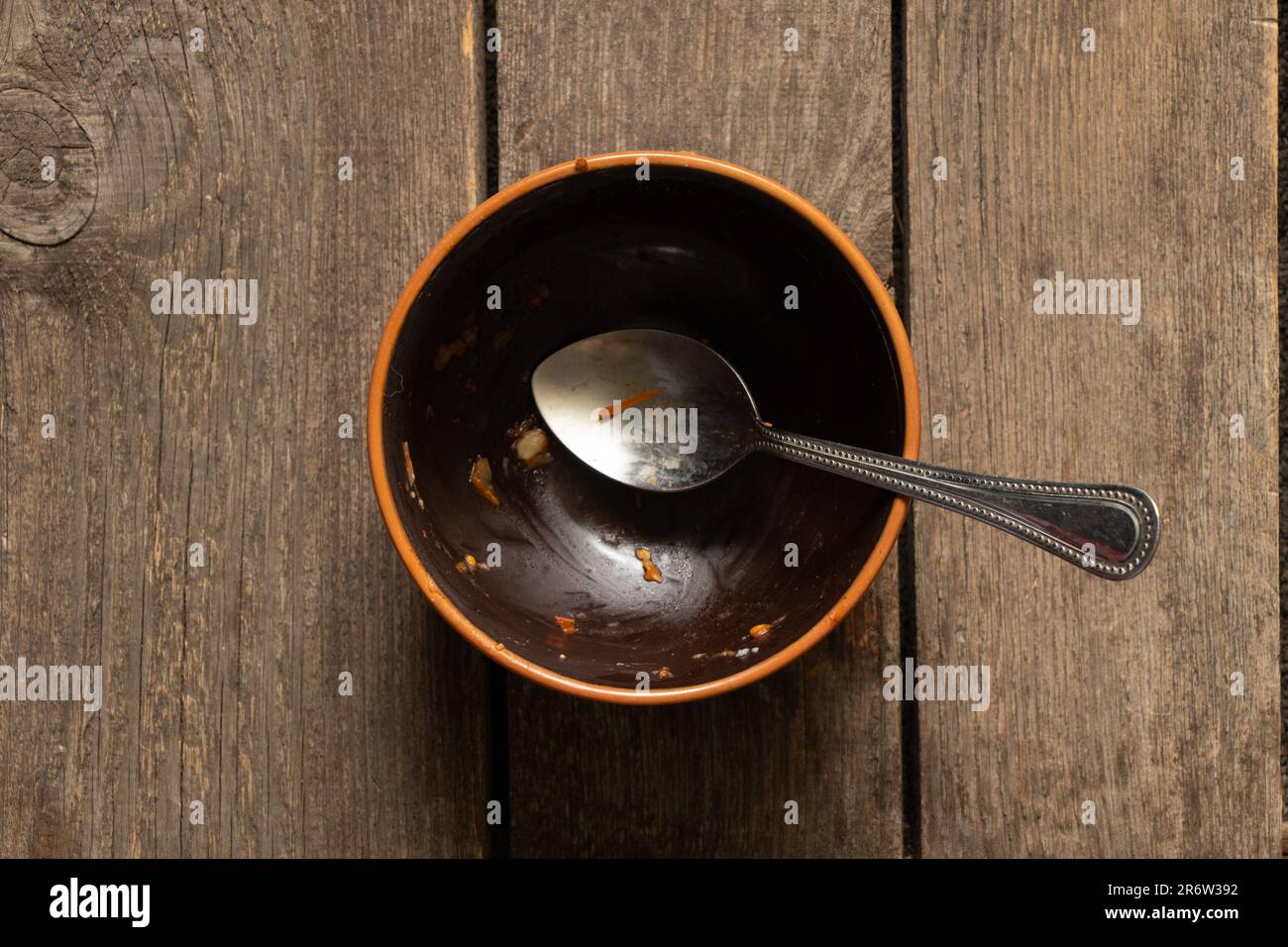assiette brune sale après le repas et cuillère sur la vieille table en bois de près Banque D'Images
