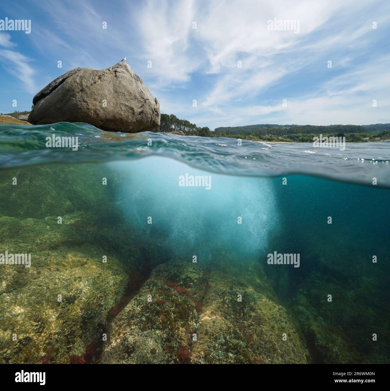 Boulder sur la rive de la mer avec des rochers sous-marins, vue partagée sur et sous la surface de l'eau, côte atlantique en Espagne, Galice, Rias Baixas Banque D'Images