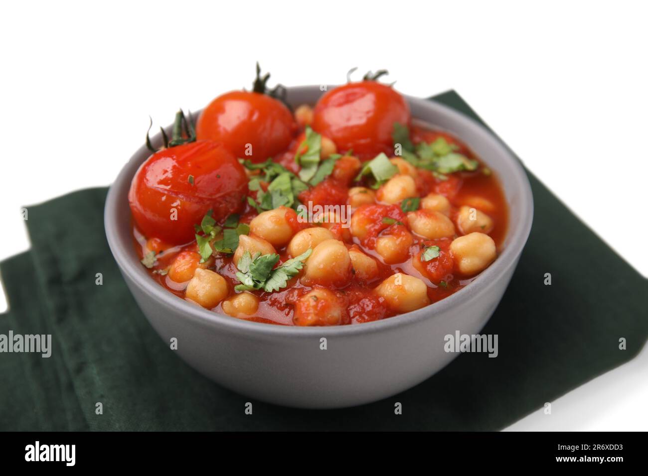 Délicieux curry de pois chiches dans un bol et tissu foncé sur fond blanc, gros plan Banque D'Images