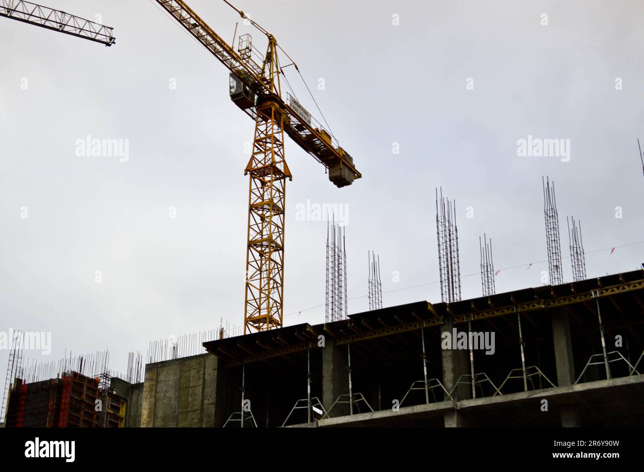 Grande grue industrielle de fret de construction puissante sur un site de construction de nouveaux bâtiments et maisons contre le ciel. Banque D'Images