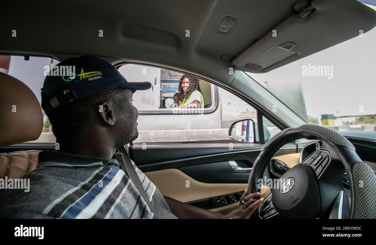 Dakar. 13th mai 2023. Leon Kossivi (à l'avant) conduit sa voiture en passant par la station de péage où son épouse Monique (à l'arrière) est en service le long de l'autoroute Ila-Touba au Sénégal, sur 13 mai 2023. POUR ALLER AVEC 'Feature: Les jeunes togolais fleurissent à travers la coopération sino-africaine Belt & Road' crédit: Li Yahui/Xinhua/Alay Live News Banque D'Images