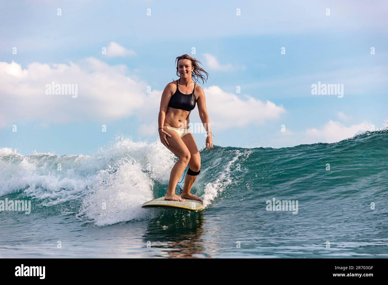 Femme surfeuse à cheval vague, Changgu, Bali, Indonésie Banque D'Images