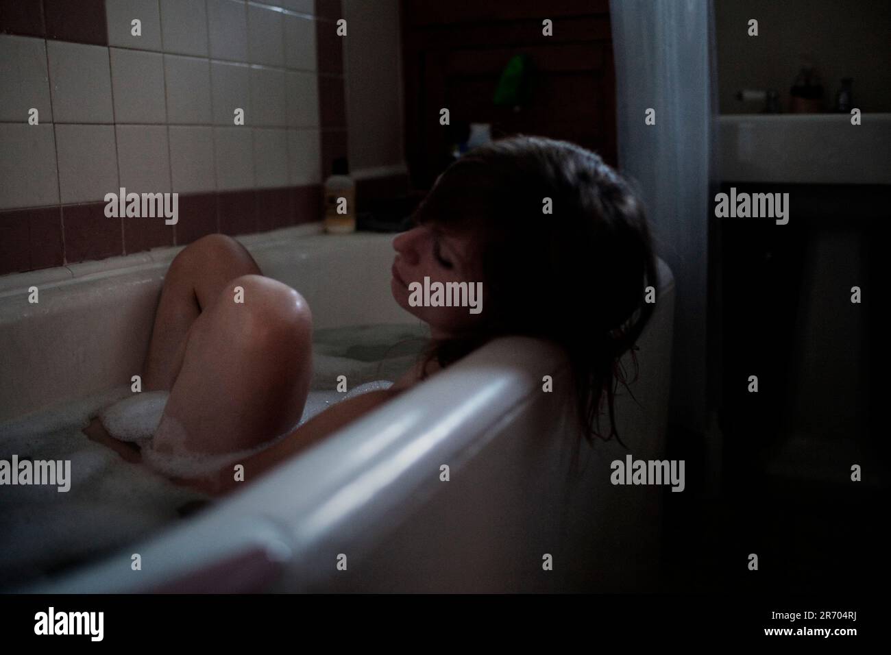 Une jeune femme rêve pendant un bain, Los Angeles, Californie. Banque D'Images