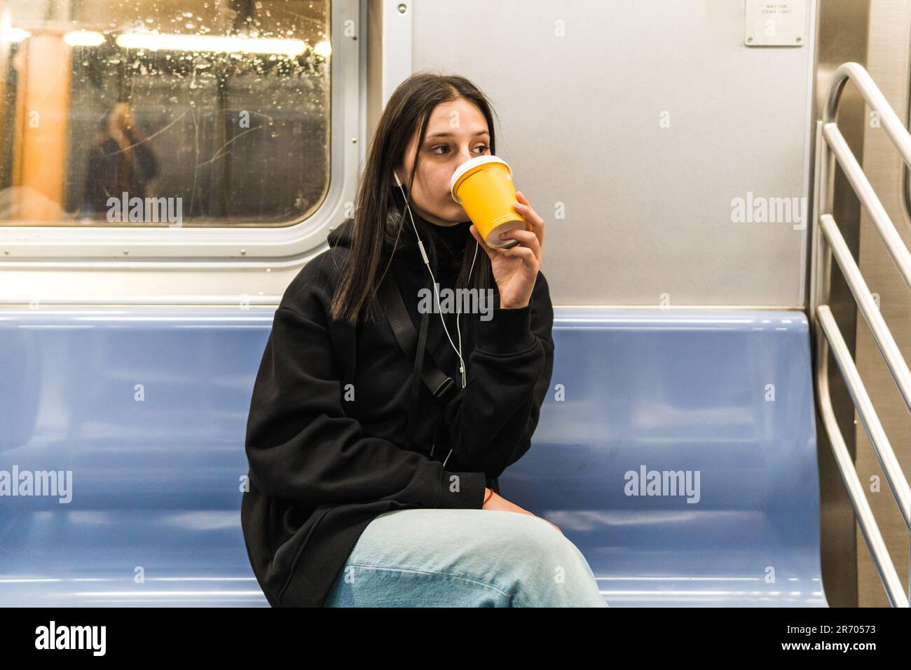une jeune femme boit du café dans le métro Banque D'Images