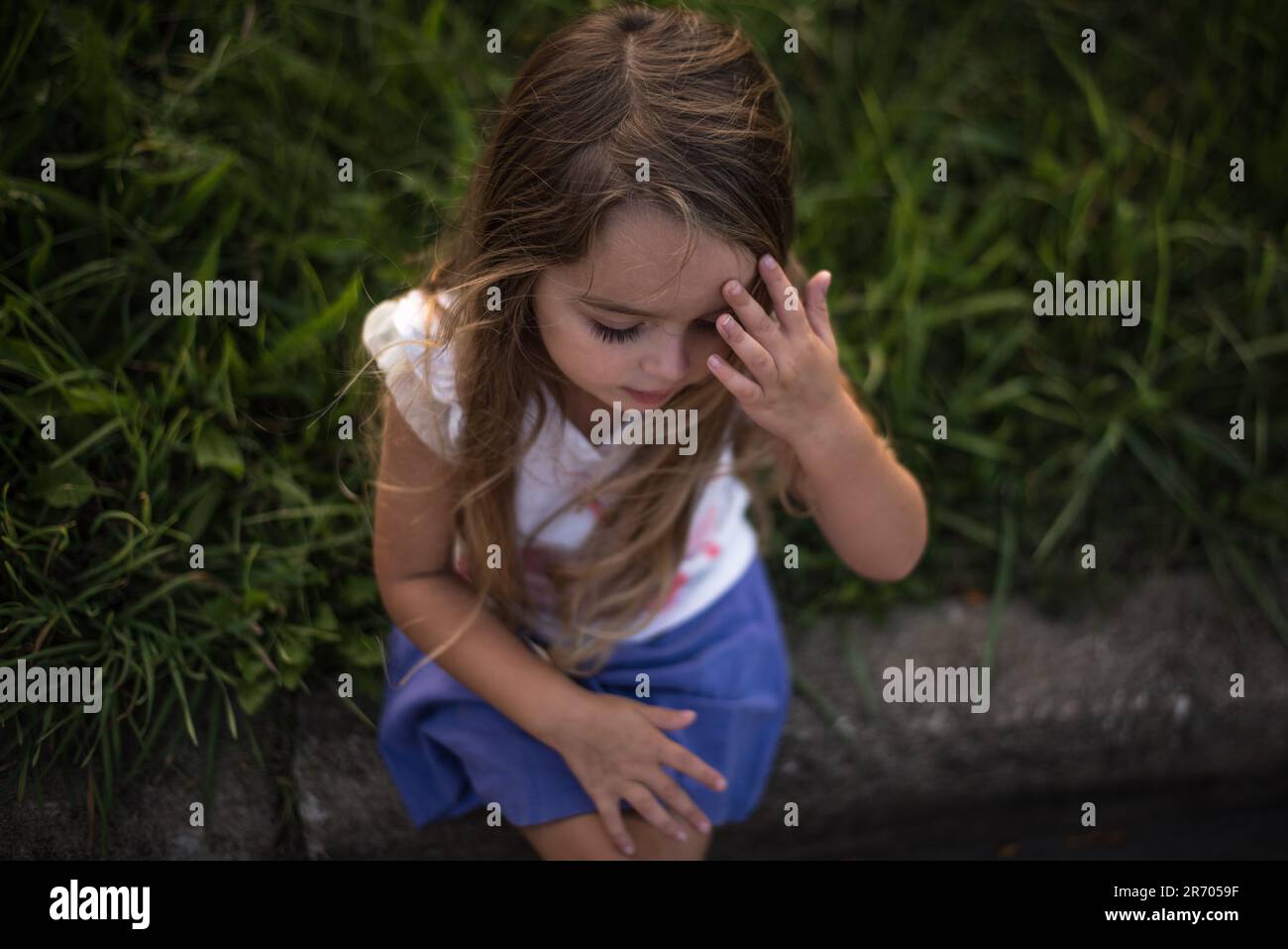 Petite fille pensant avec la main sur le front Banque D'Images