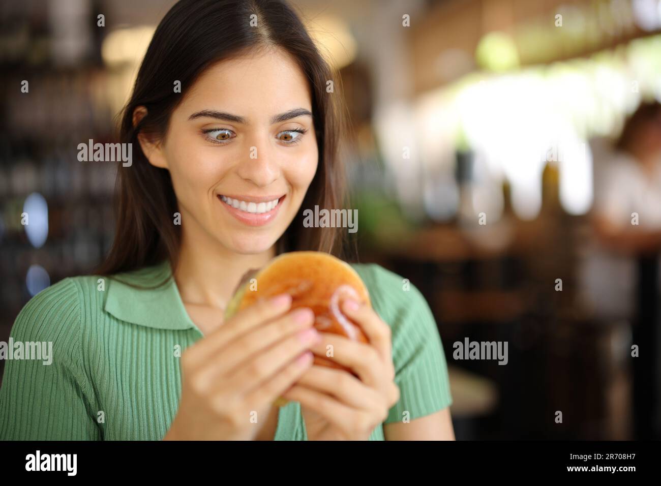 Une femme de glutton regardant un hamburger dans un bar intérieur Banque D'Images