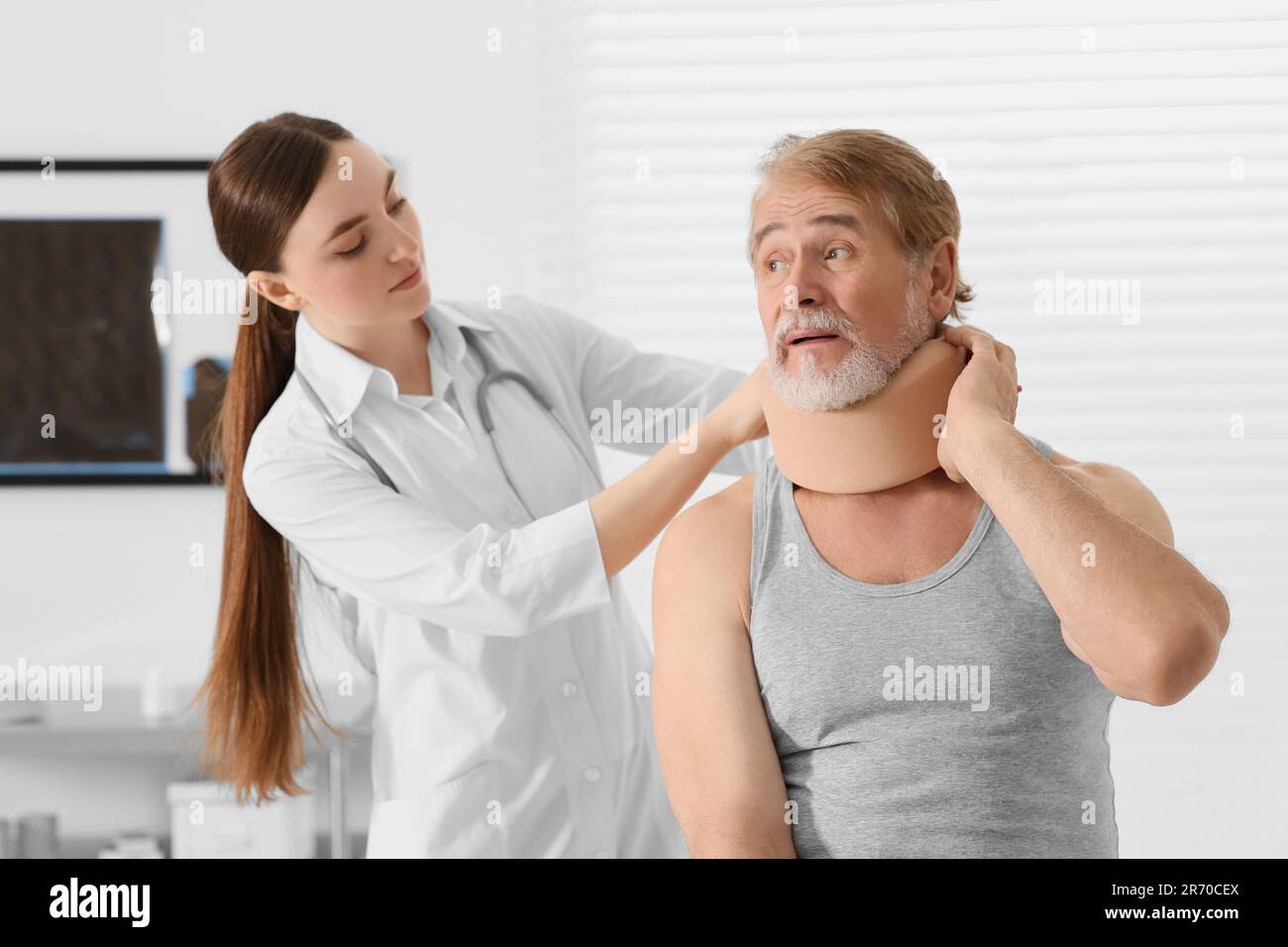 Orthopédiste appliquant le col cervical sur le cou du patient en clinique Banque D'Images