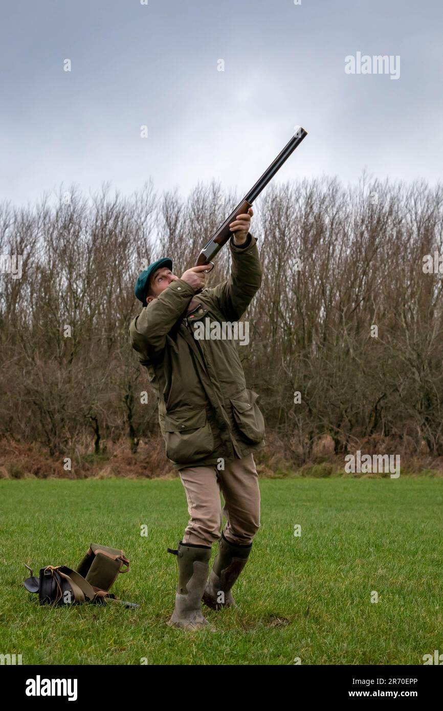 Un homme du Caucase se tient avec une arme à feu relevée dans ses mains, pointant l'arme vers le ciel dans un geste de célébration Banque D'Images