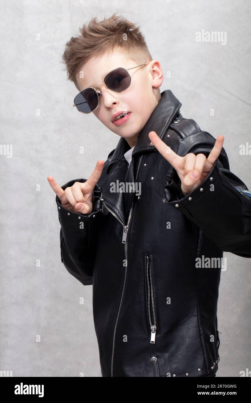 Portrait d'un garçon en métal lourd dans des lunettes de soleil. Adorable  adolescent dans une veste en cuir faisant un rock and roll signe Photo  Stock - Alamy