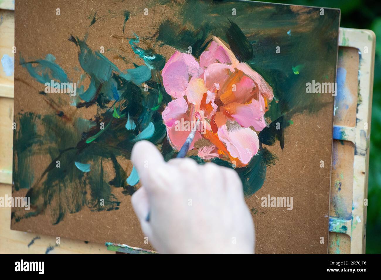 Main de peintre tenant un pinceau pour peindre une fleur. Banque D'Images