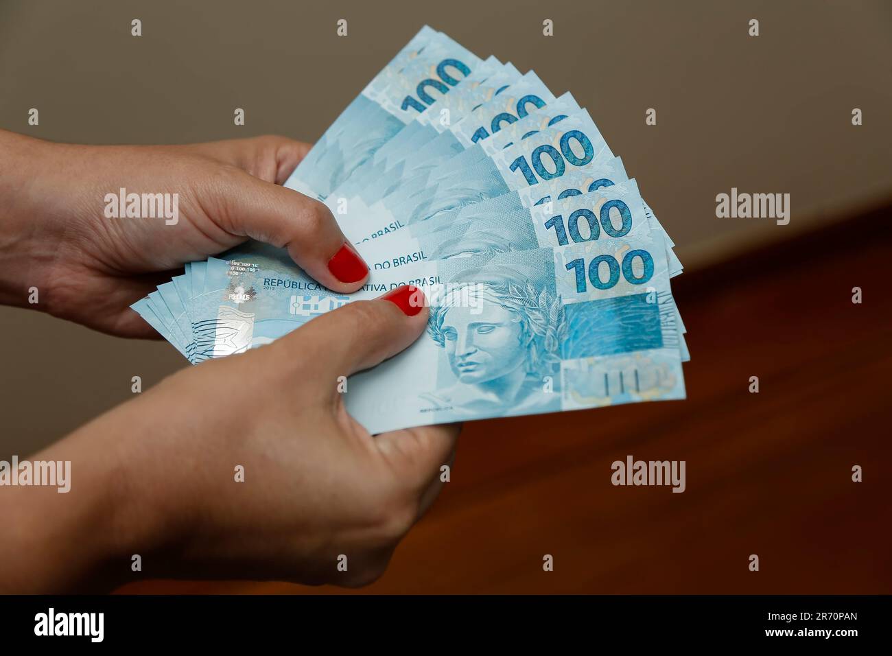 Plusieurs centaines de factures réelles - argent du Brésil dans une main de womans avec des ongles rouges Banque D'Images