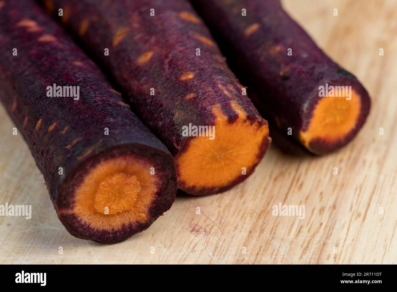 Tranches de carottes violet-orange sur la table, plusieurs racines de carottes pelées aux teintes bordeaux et orange Banque D'Images