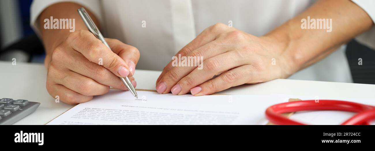 Femme médecin dans la robe médicale mettre signe sur le presse-papiers avec des documents Banque D'Images