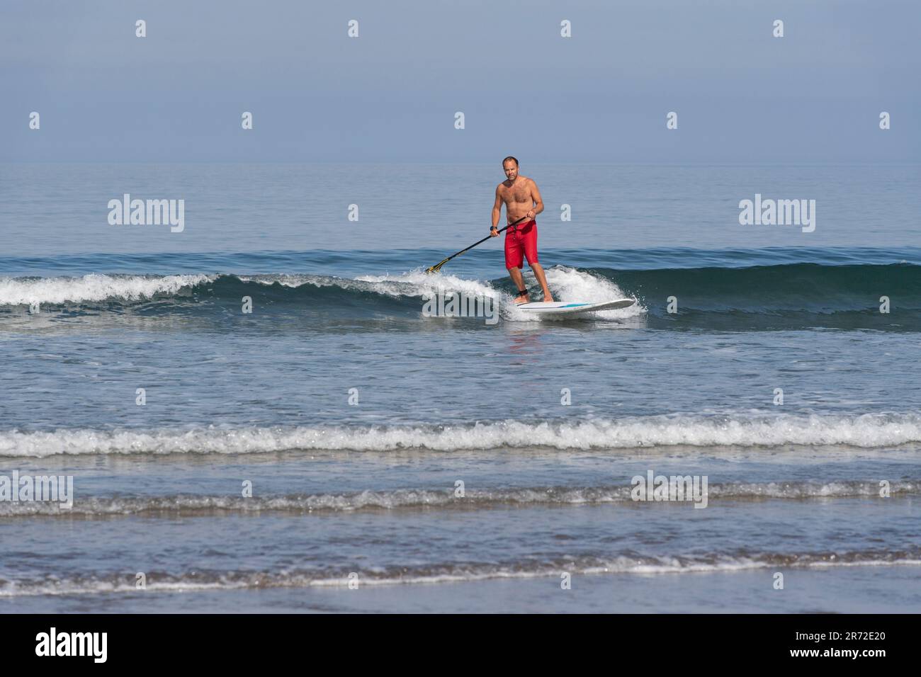 homme sur un paddle board dans le surf Banque D'Images