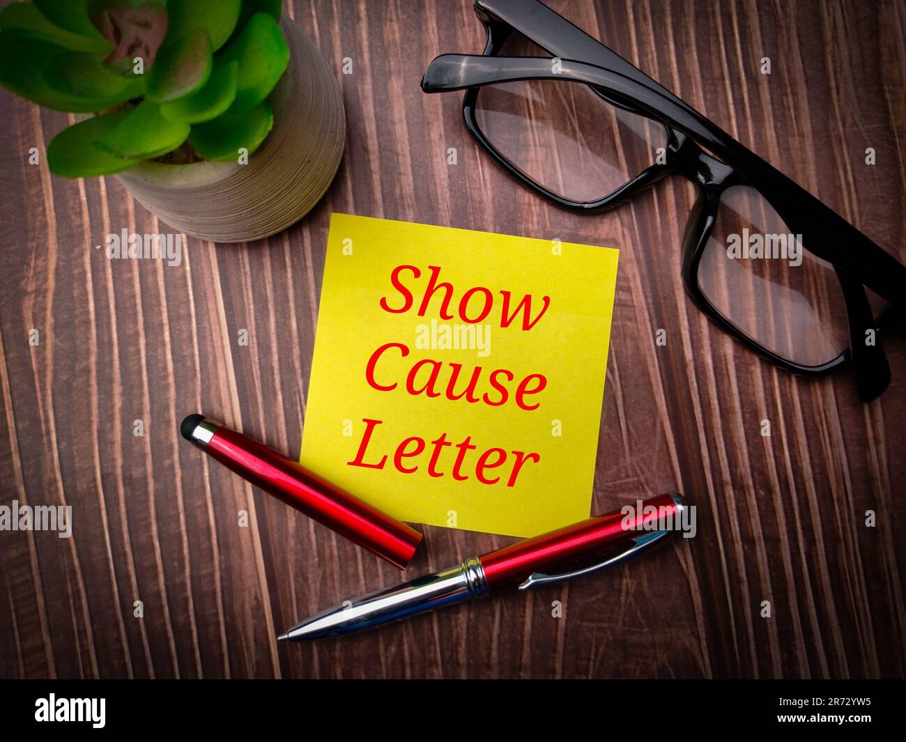 Une note avec les mots « Afficher la lettre de cause » sur un bureau en bois Banque D'Images