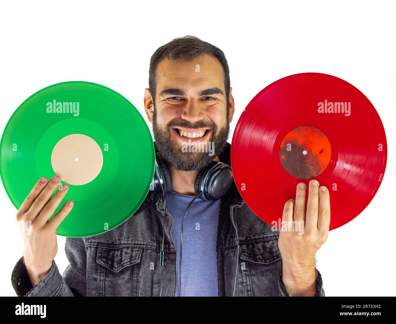 Jeune homme tenant et comparant des vinyles rouges et verts sur fond blanc Banque D'Images