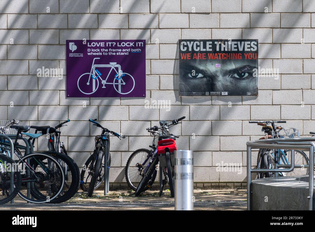 Porte-vélos, bicyclettes, vélos, vélos avec panneaux de sécurité notices d'information en dehors de l'Université de Portsmouth, Hampshire, Angleterre, Royaume-Uni Banque D'Images
