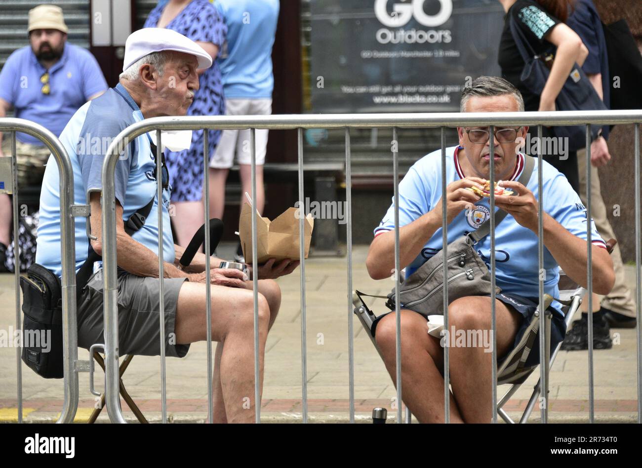 Manchester, Royaume-Uni. 12th juin 2023. Les fans apprécient un en-cas en attendant que le Manchester City football Club se prépare à organiser un défilé de victoire en bus à haut rendement dans le centre de Manchester, au Royaume-Uni, pour marquer la victoire des aigus : la Premier League, la FA Cup et la Champions League. Samedi, Man City a battu Inter Milan à Istanbul pour obtenir la victoire de la Ligue des Champions. La parade des bus à toit ouvert a traversé le centre-ville de Manchester et a été suivie par de grandes foules enthousiastes, malgré un orage et de fortes pluies. Crédit : Terry Waller/Alay Live News Banque D'Images