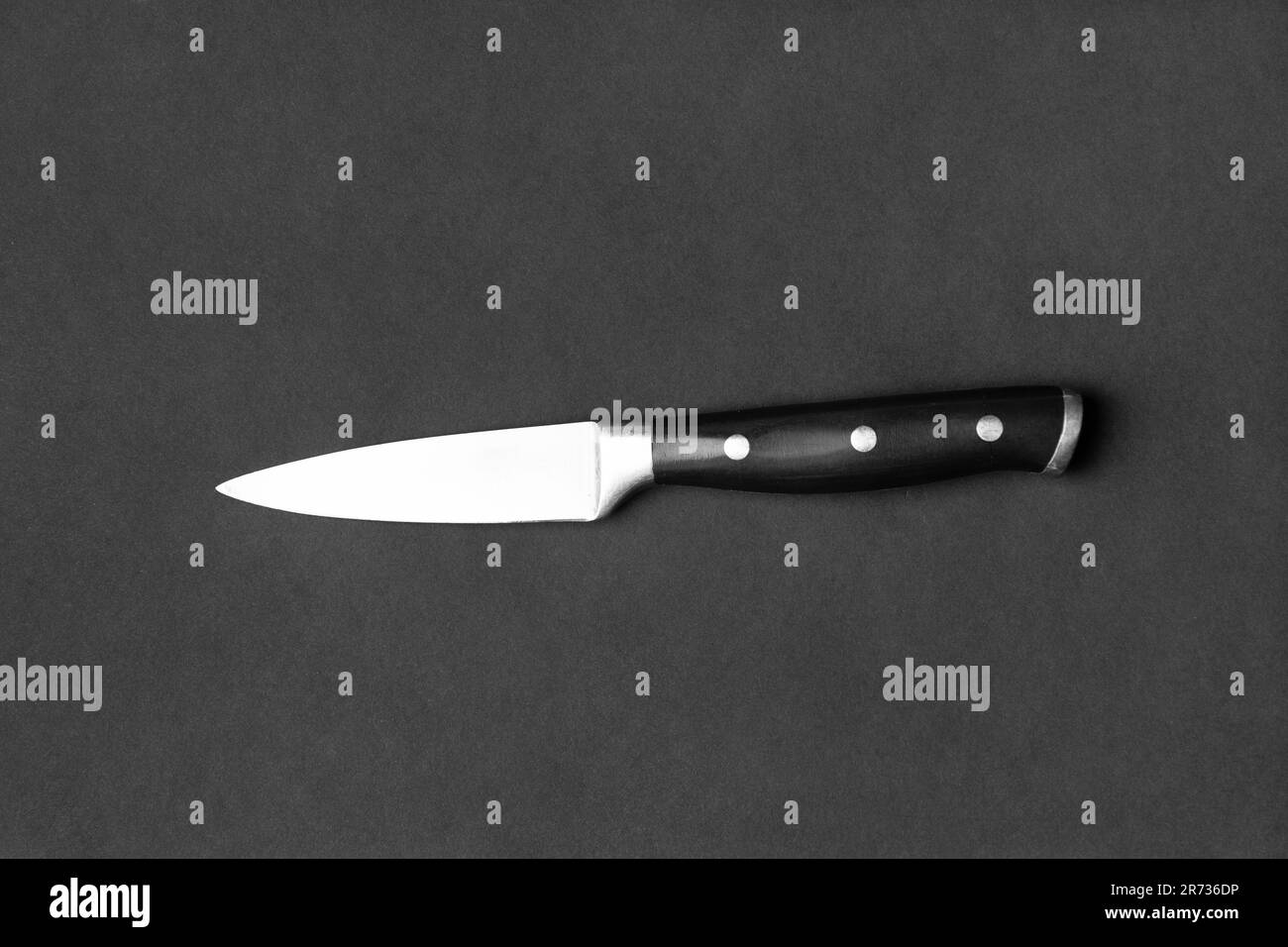 Couteau de cuisine avec poignée noire sur fond noir. Couteau sur fond sombre vue de dessus. Ustensiles de cuisine. Couteau à lame large. Banque D'Images