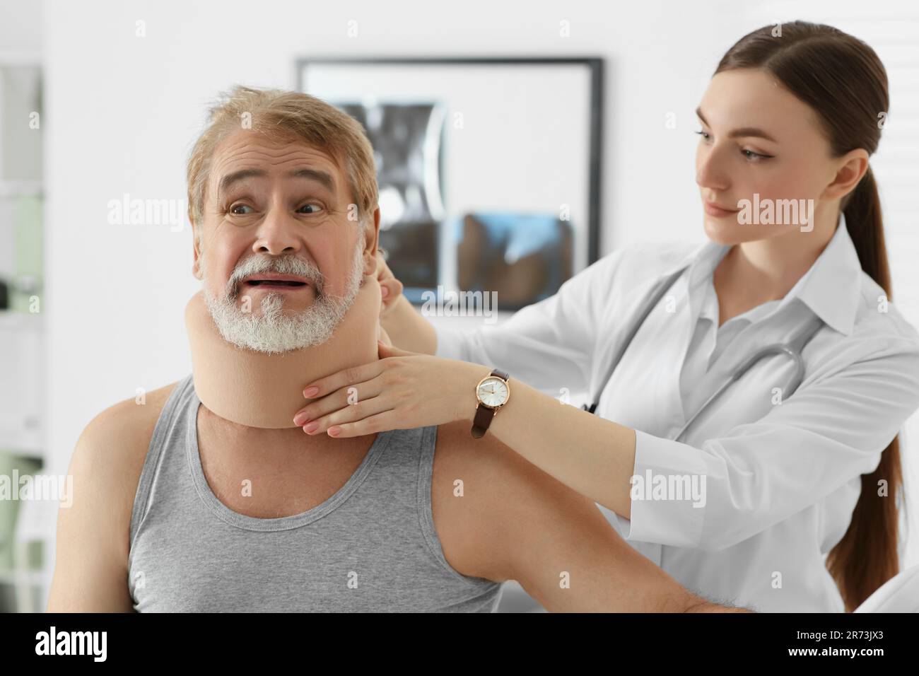 Orthopédiste appliquant le col cervical sur le cou du patient en clinique Banque D'Images