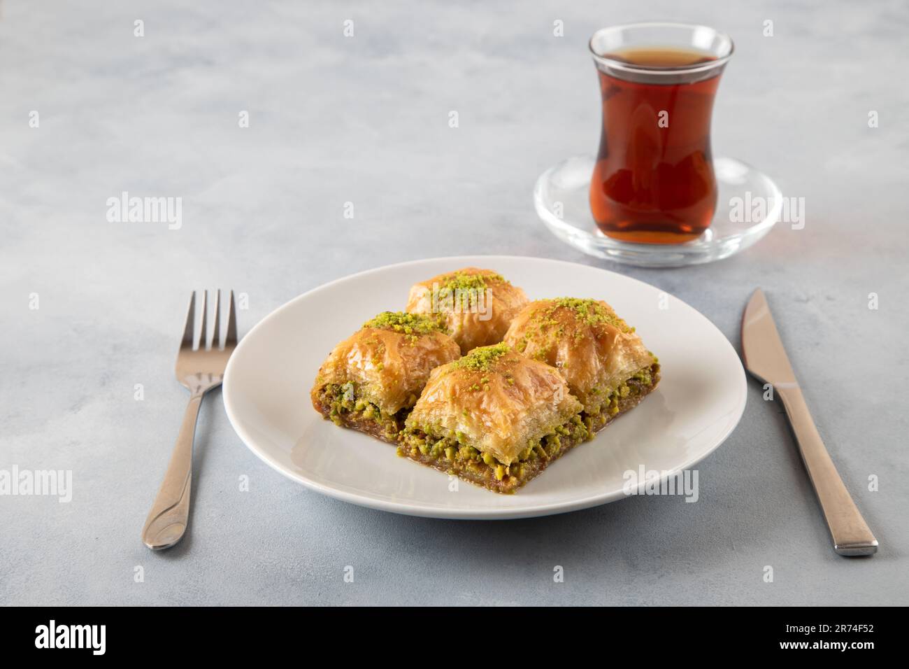 Pistache baklava sur une assiette blanche avec thé turc. Baklava turque traditionnelle et thé sur fond bleu clair Banque D'Images
