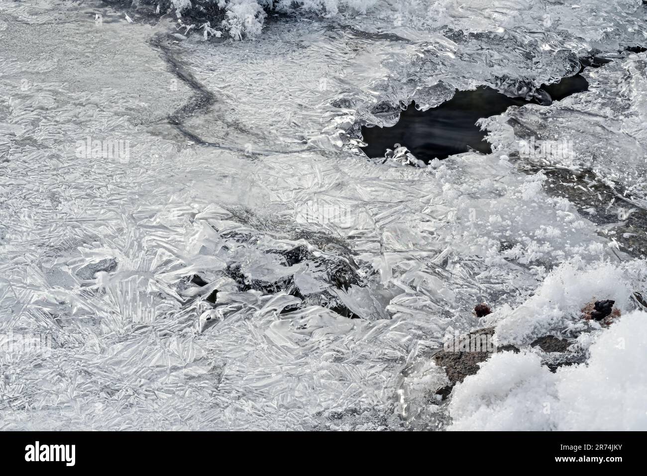 Rivière gelée en hiver recouverte de glace cristalline mince, photo à angle bas, trou avec eau qui coule sous Banque D'Images