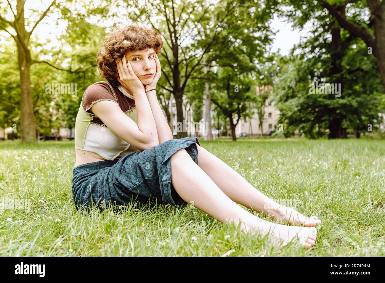 Portrait d'une jeune fille modèle souriant assis sur l'herbe dans le parc de la ville Banque D'Images