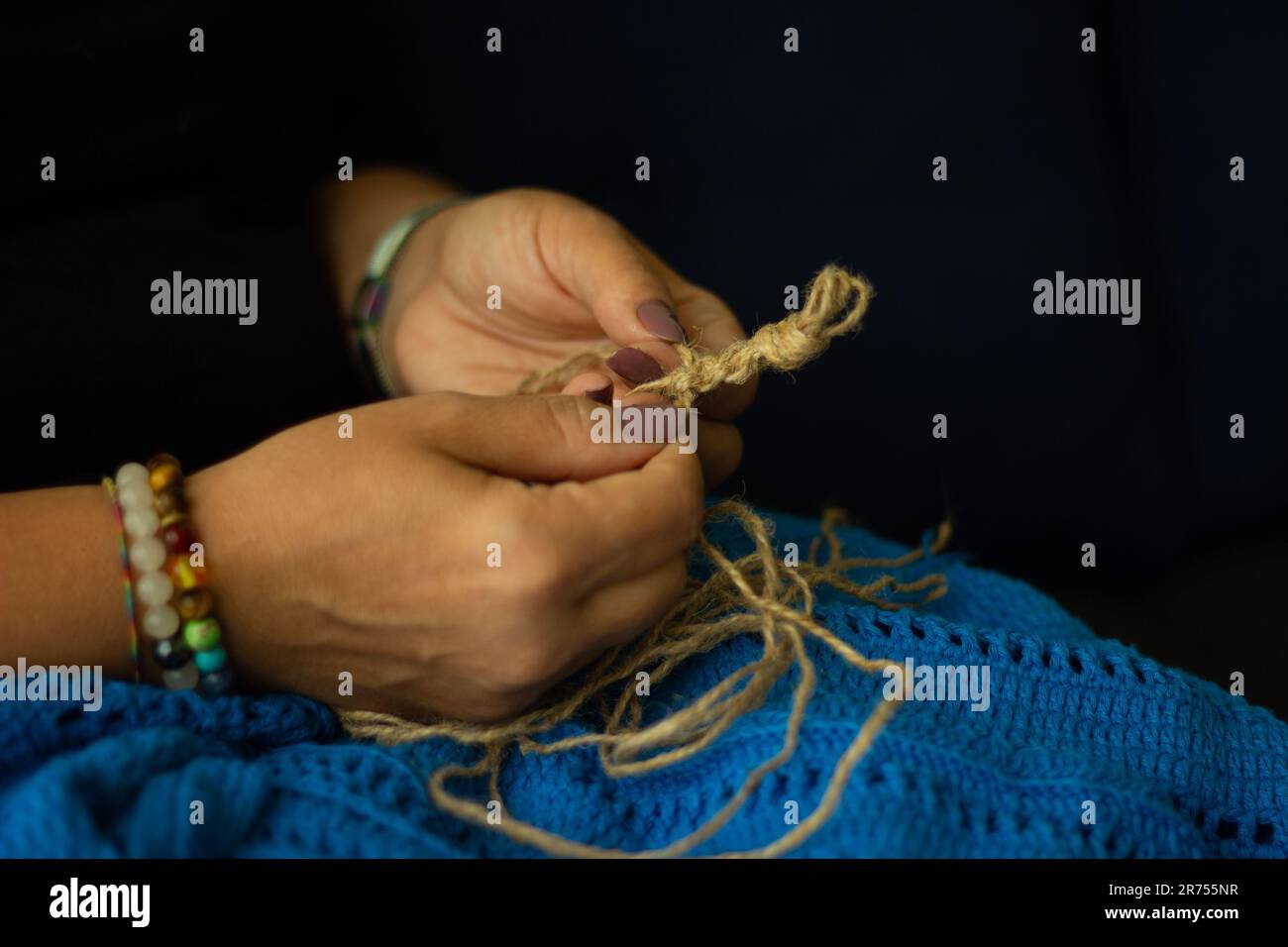 Les mains d'une femme et le fil de jute et le fragment d'un motif tricoté. tricot écologique naturel, artisanat et passe-temps, décoration écologique. Banque D'Images