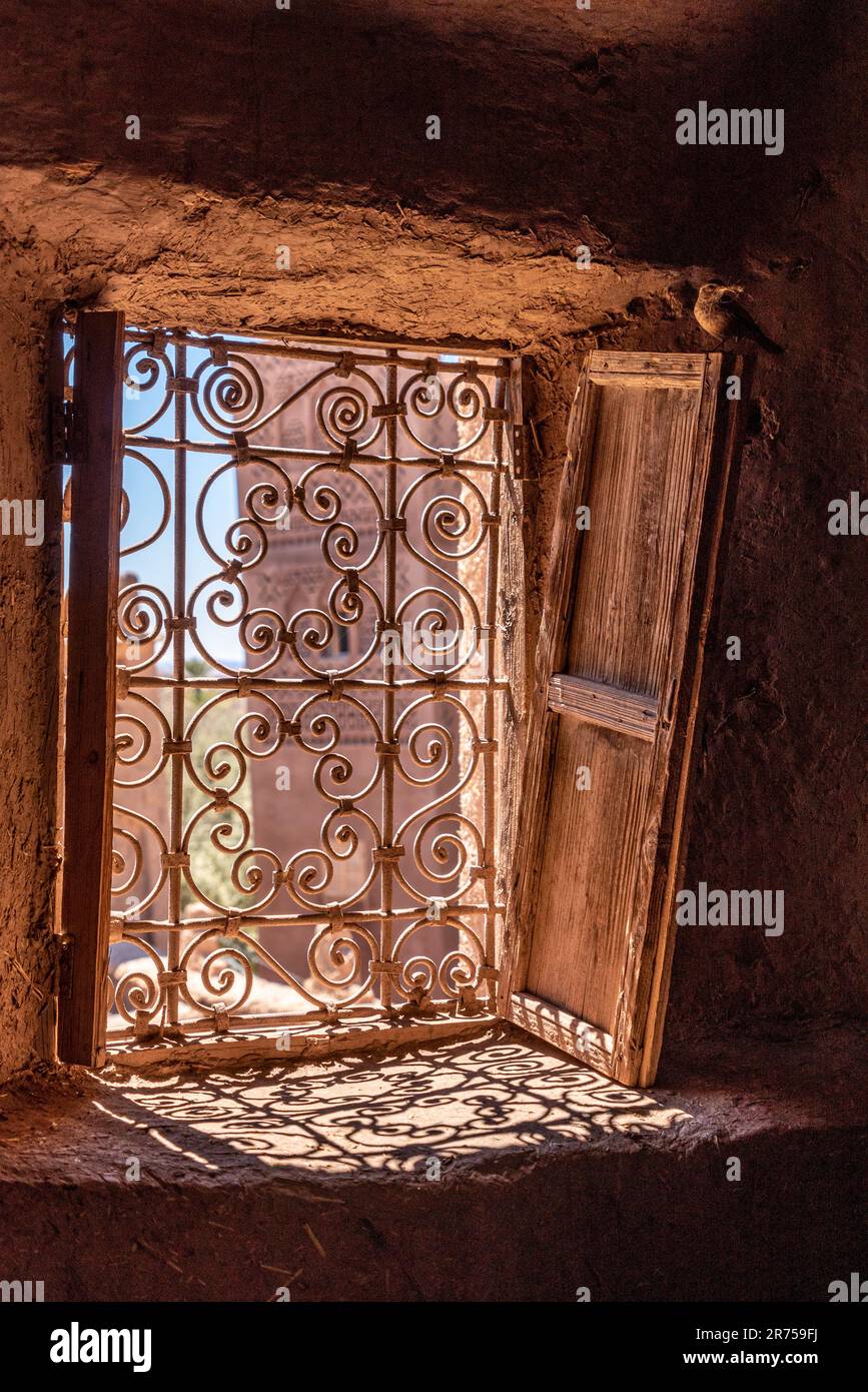 Une grille de fenêtre ornée et des volets en bois abandonnés dans une kasbah marocaine typique Banque D'Images