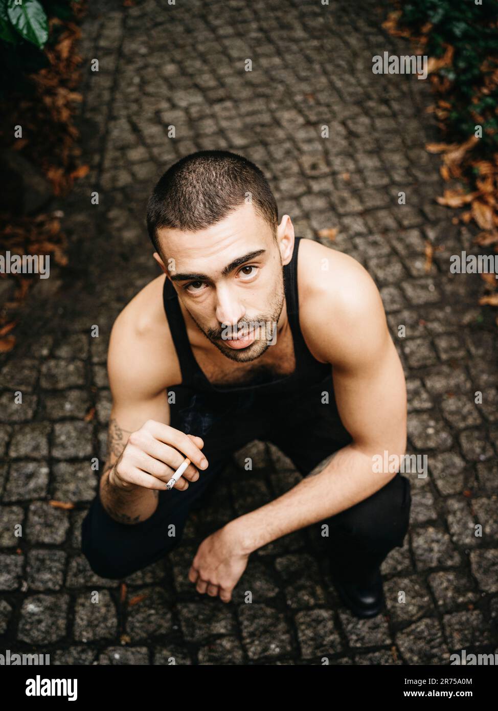 homme, cheveux courts, cigarette, squat, d'en haut Banque D'Images