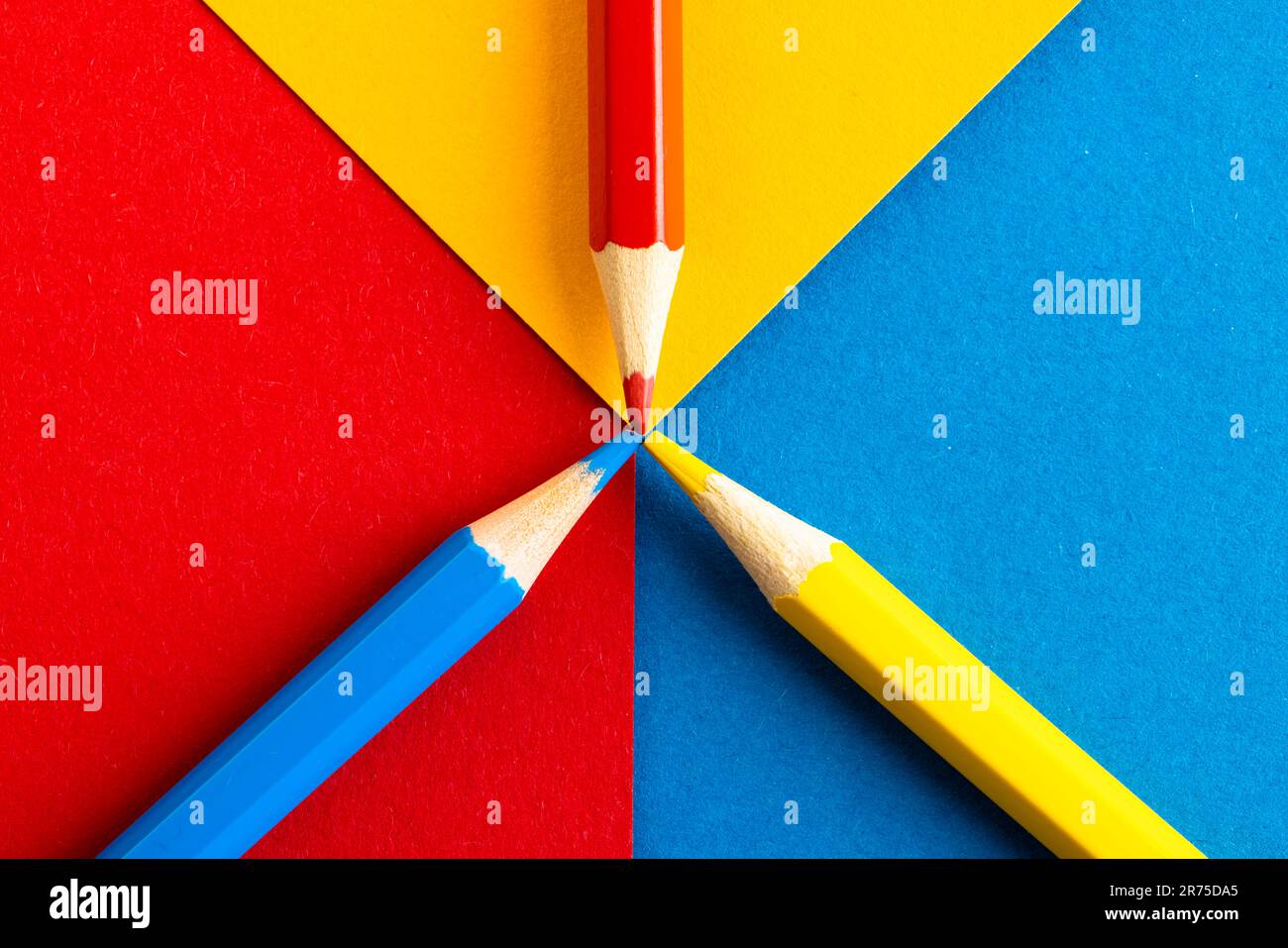 Gros plan de crayons rouges, jaunes et bleus avec espace de copie sur fond rouge, jaune et bleu. Matériel scolaire, écriture, coloriage, dessin, apprentissage, Banque D'Images