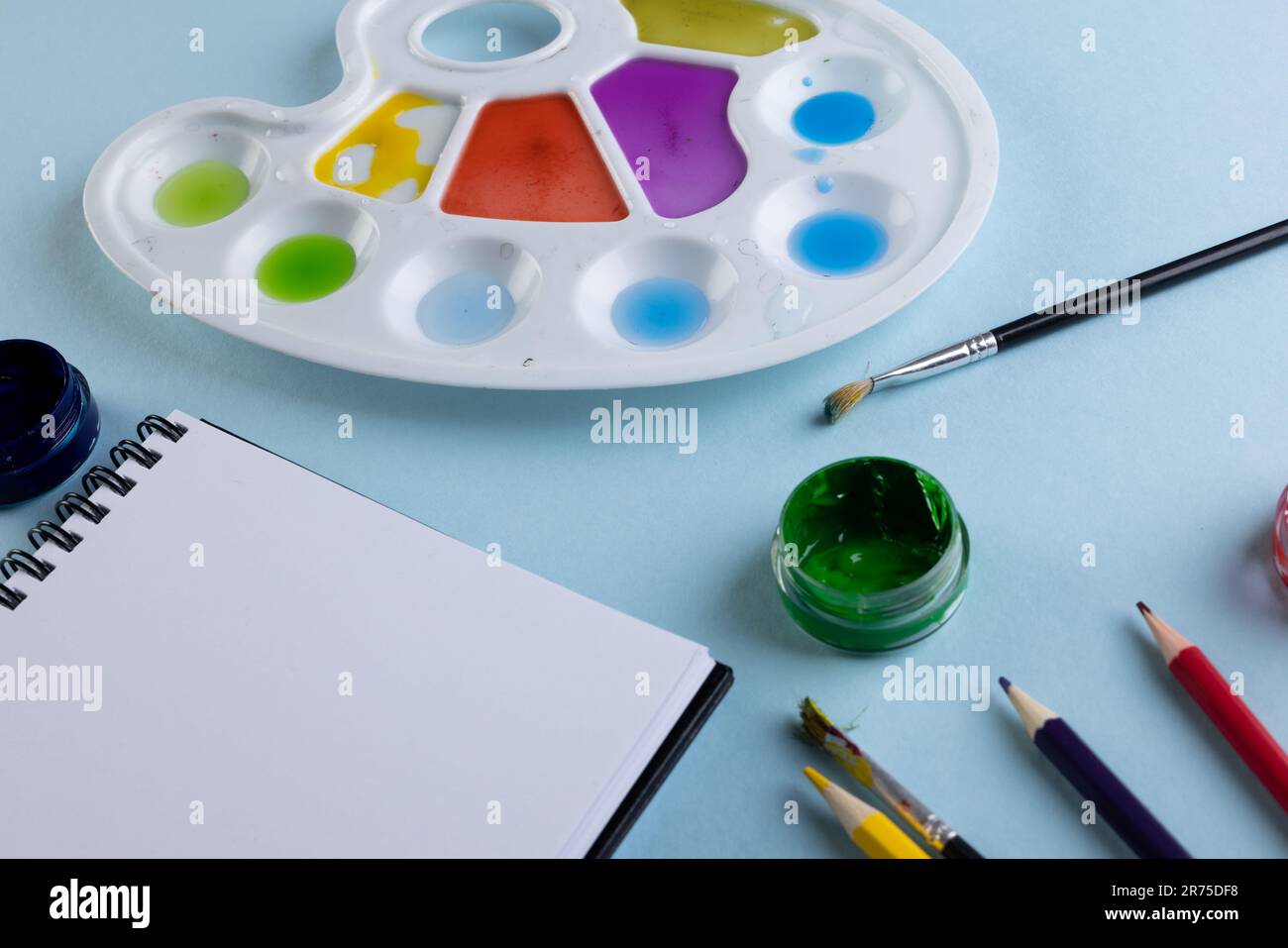 Gros plan des peintures, des carnets et des pinceaux avec espace de copie sur fond bleu. Retour à l'école, art, peinture, matériel scolaire, apprentissage, école et edu Banque D'Images