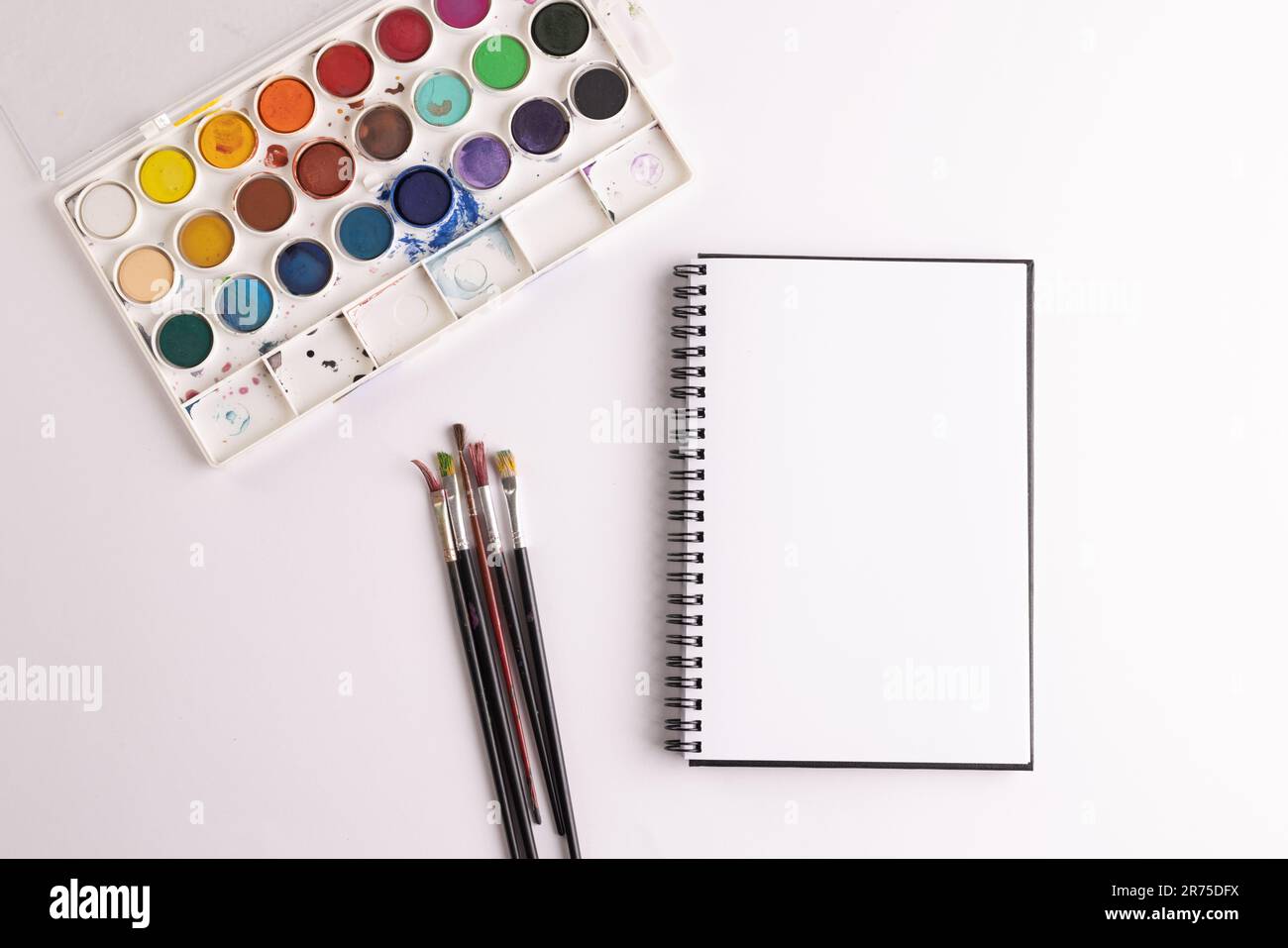 Gros plan de peintures, carnets et pinceaux avec espace de copie sur fond blanc. Retour à l'école, art, peinture, matériel scolaire, apprentissage, école et ed Banque D'Images